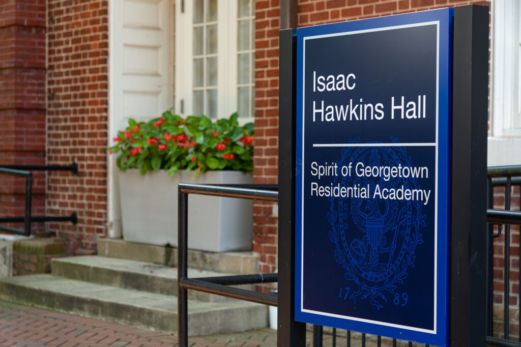 A blue way finding sign for Isaac Hawkins Hall in front of the building