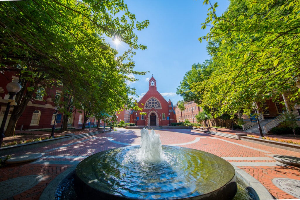 Dahlgren Chapel, a small brick steepled building, sits among a group of trees. In front of it is a large round water fountain.