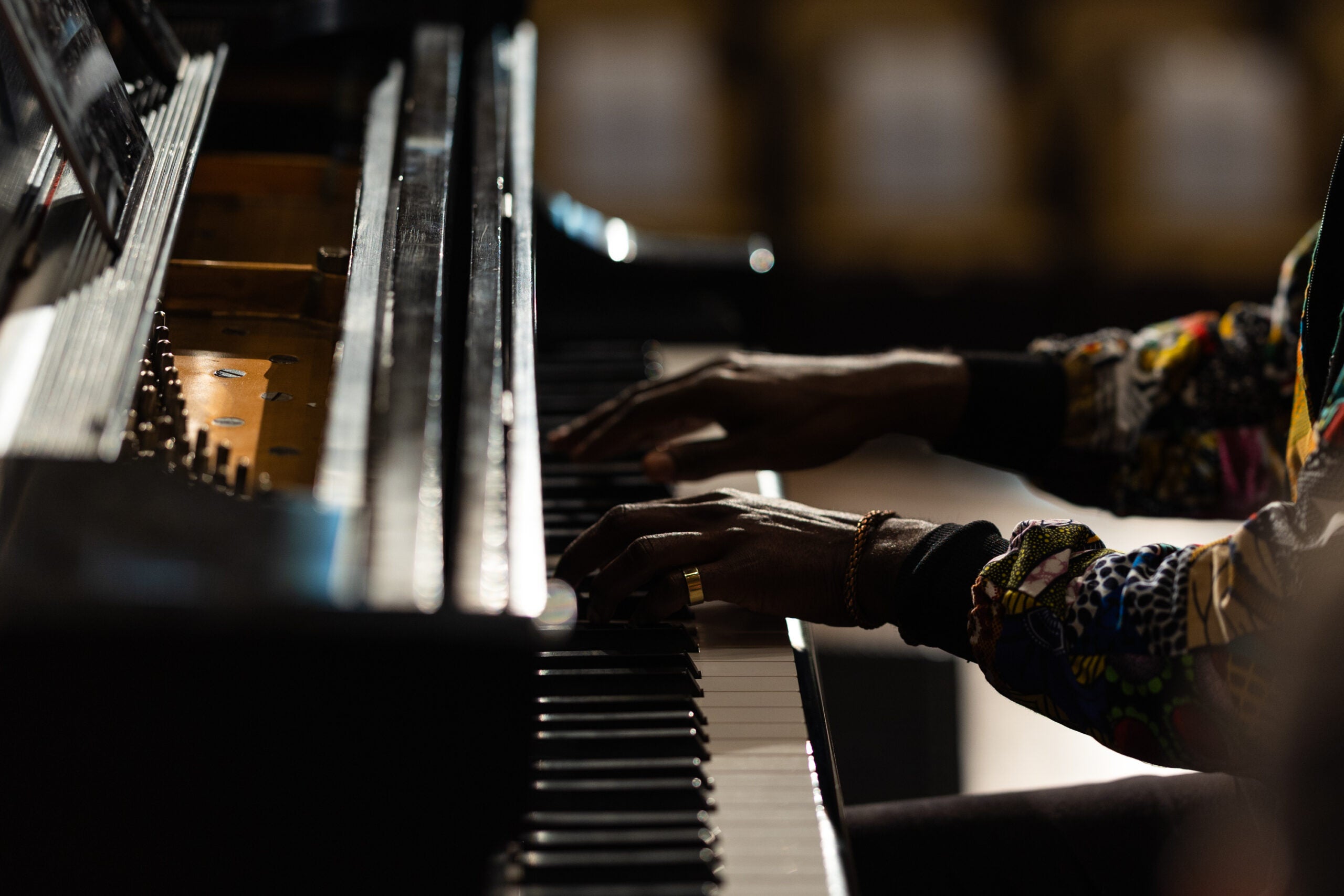 A musician's hands play at a grand piano.